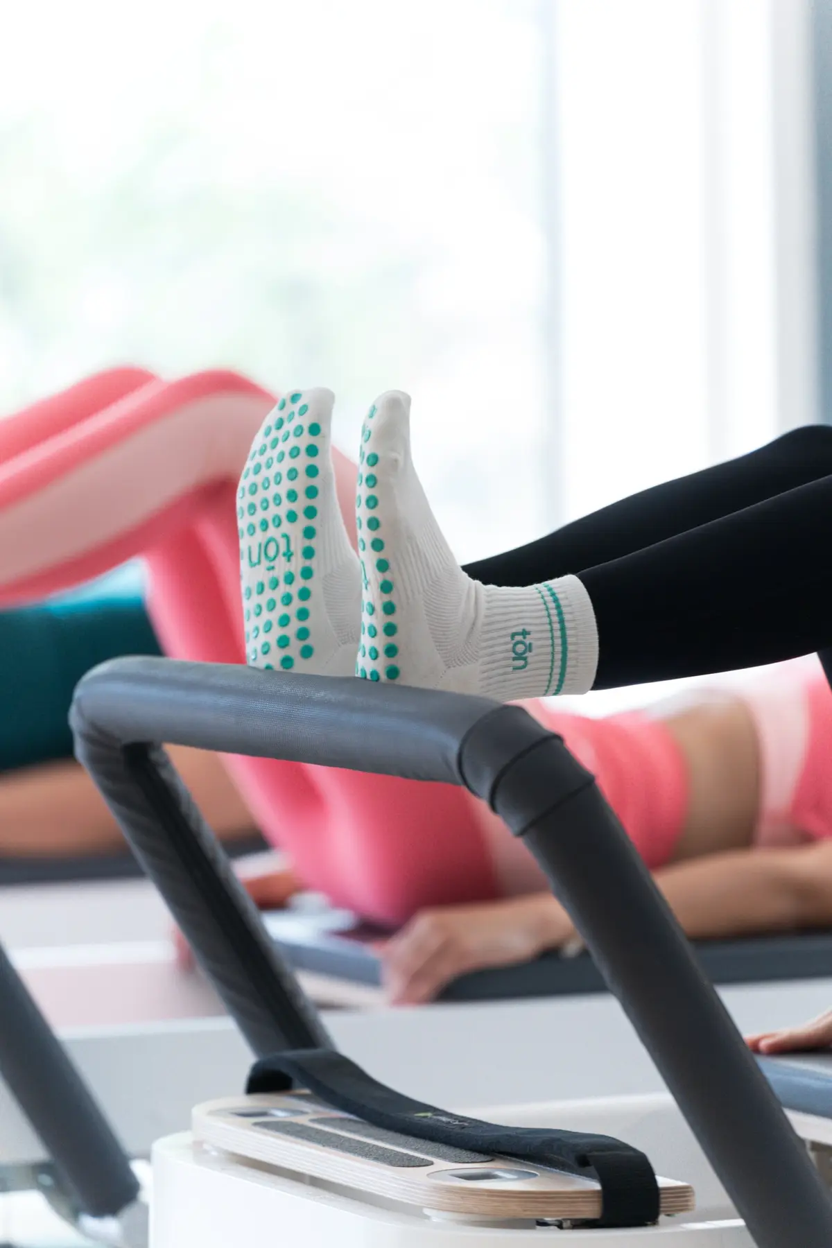 Tōn Pilates grip socks resting on the footbar of a Balanced Body Allegro 2 Reformer in the Astoria studio.